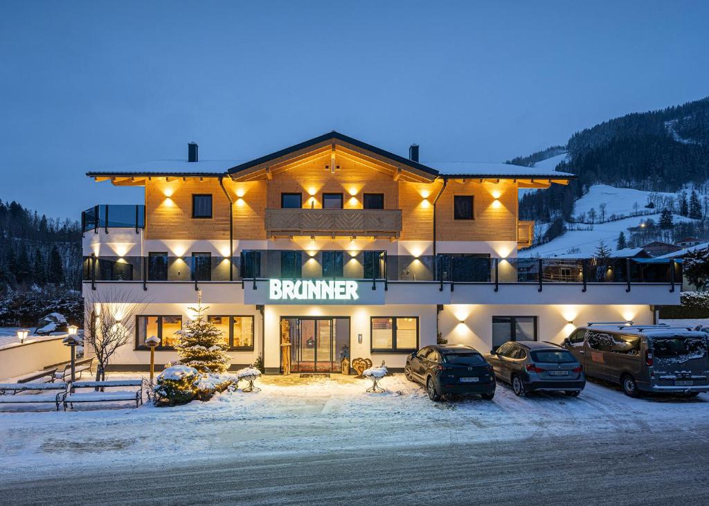 ein Gebäude mit Autos, die vor ihm im Schnee geparkt sind in der Unterkunft Hotel Brunner - Reiteralm in Schladming