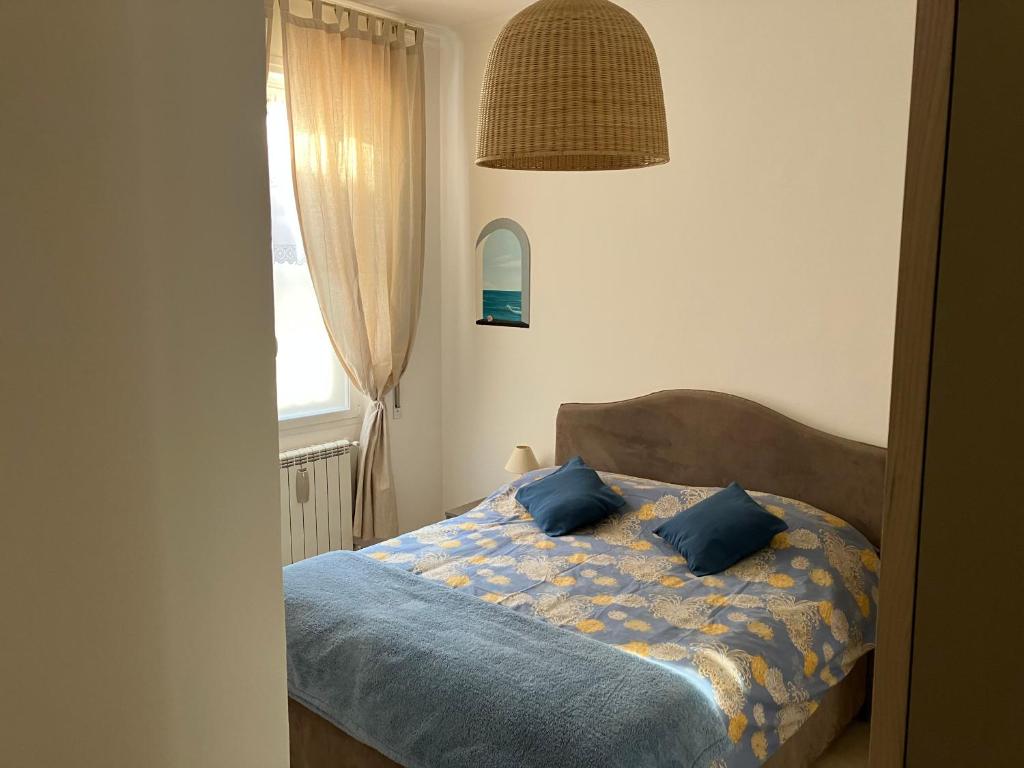 een slaapkamer met een bed met blauwe kussens en een raam bij Aria di mare in Sanremo