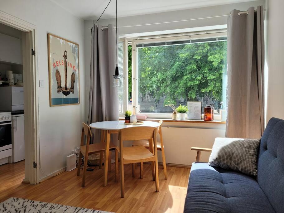 a living room with a table and a window at PunavuoriPad - Modern Apt. with Park Views in Design District in Helsinki