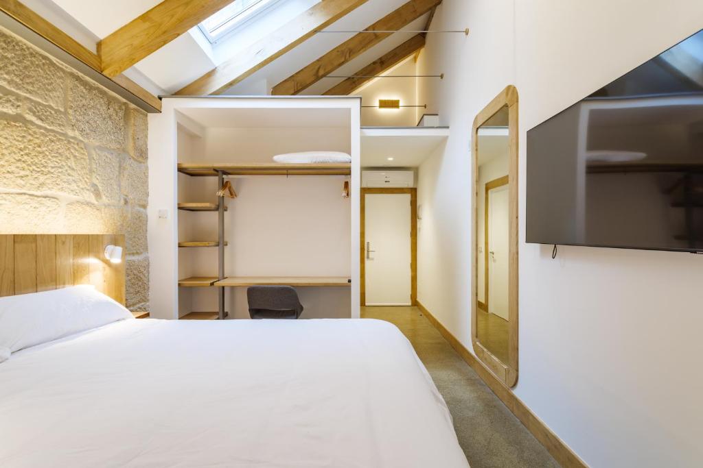 a bedroom with a bed and a flat screen tv at La Fonda in Pontevedra