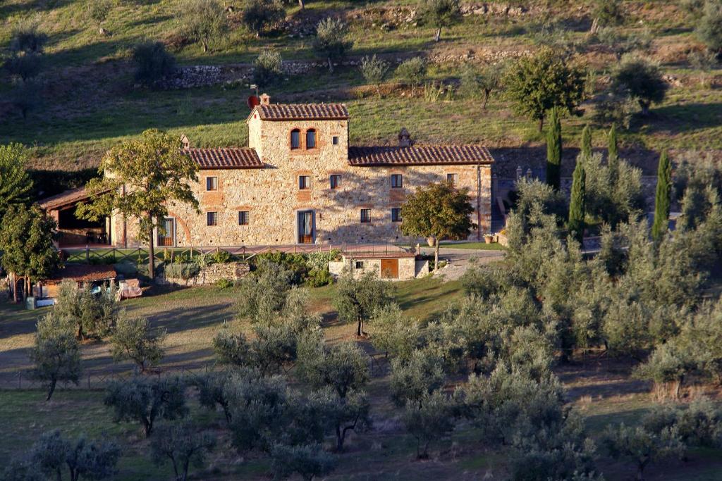 uma grande casa de pedra numa colina com árvores em Agriturismo San Martino em Quarrata