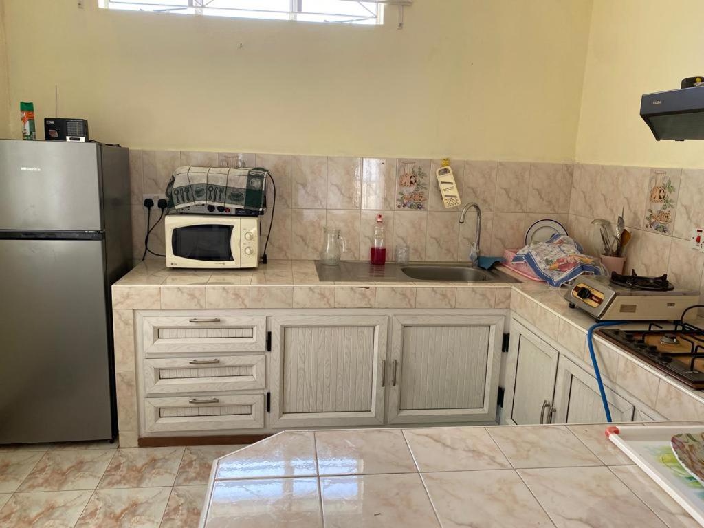 eine Küche mit einem Kühlschrank und einer Mikrowelle in der Unterkunft Shero Villa in Flic-en-Flac