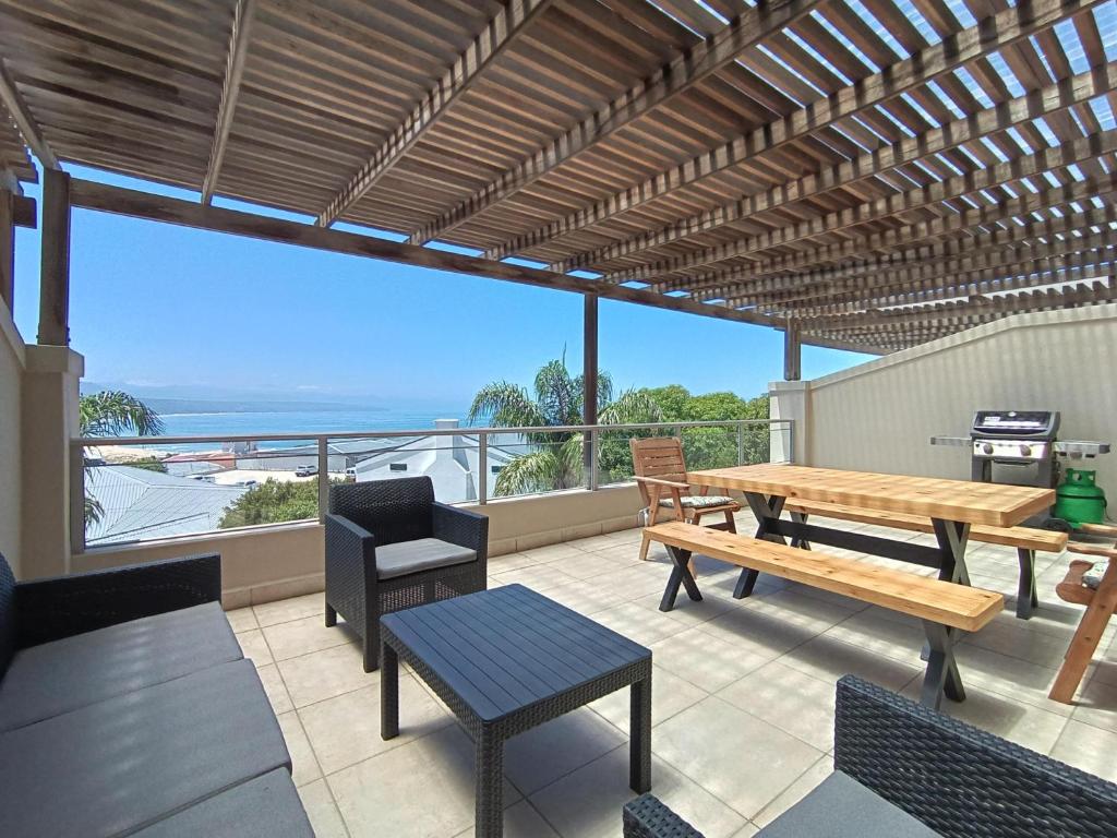 a patio with tables and chairs and a view of the ocean at The Aqua - Sleeps 4 - Patio & Sea Views in Plettenberg Bay