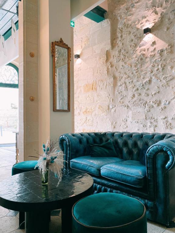 a living room with a blue couch and a table at LOLA Boutique Hôtel - Bordeaux Centre in Bordeaux