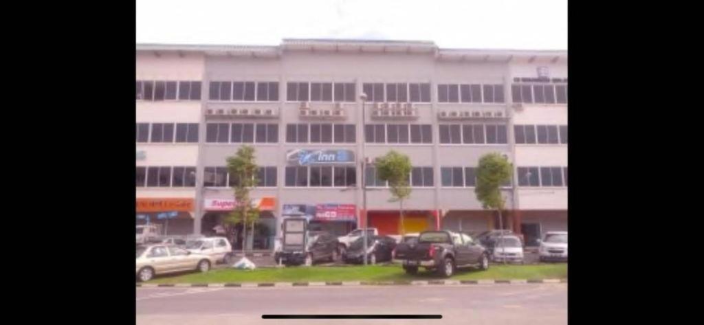 a large white building with cars parked in front of it at Super OYO 90579 U Inn in Miri