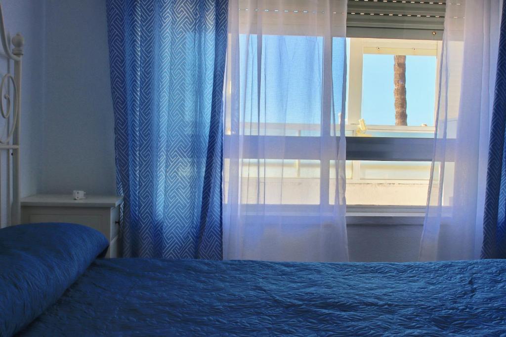 Schlafzimmer mit einem Bett und einem Fenster mit Vorhängen in der Unterkunft AranPe PLAYA CÁDIZ in Cádiz
