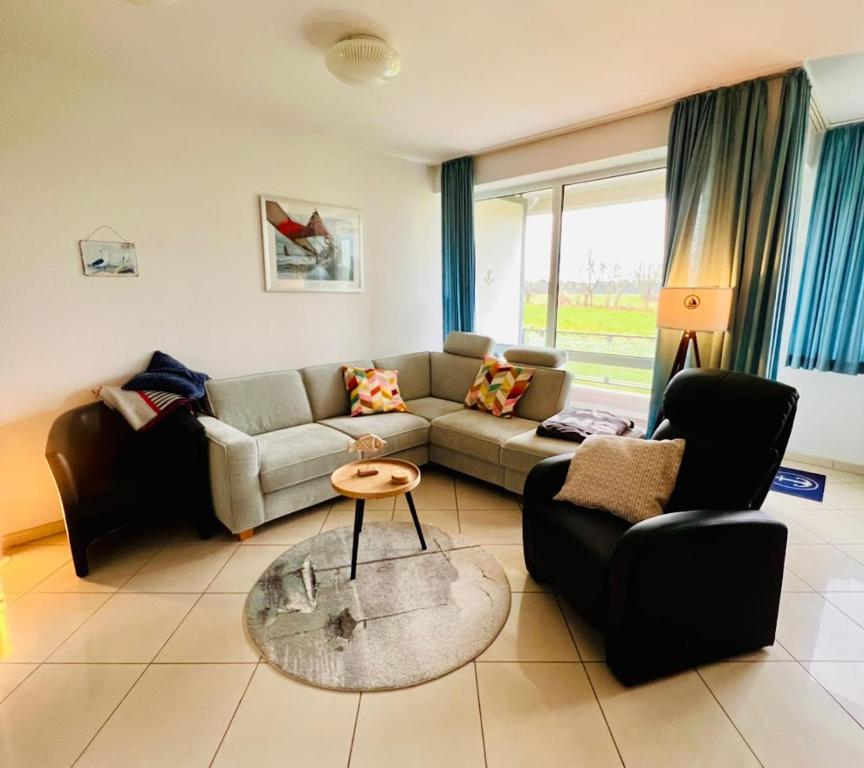 ein Wohnzimmer mit einem Sofa und einem Tisch in der Unterkunft Haus Vogelsand Whg 307 in Cuxhaven