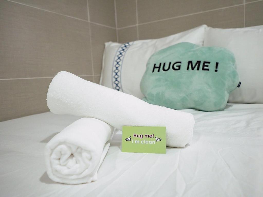 a roll of towels on a bed with a hug me sign at SAAN INN in Hong Kong