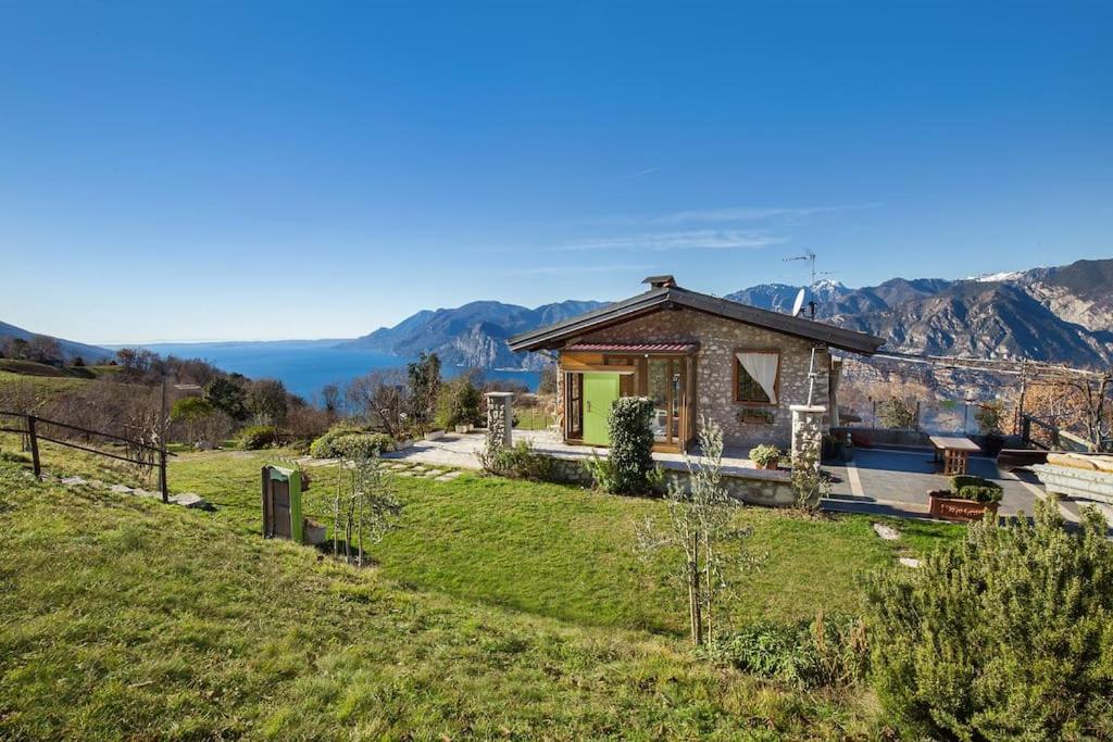 una pequeña casa en una colina con montañas en el fondo en Casale Faigolo-Vista lago, en Navene