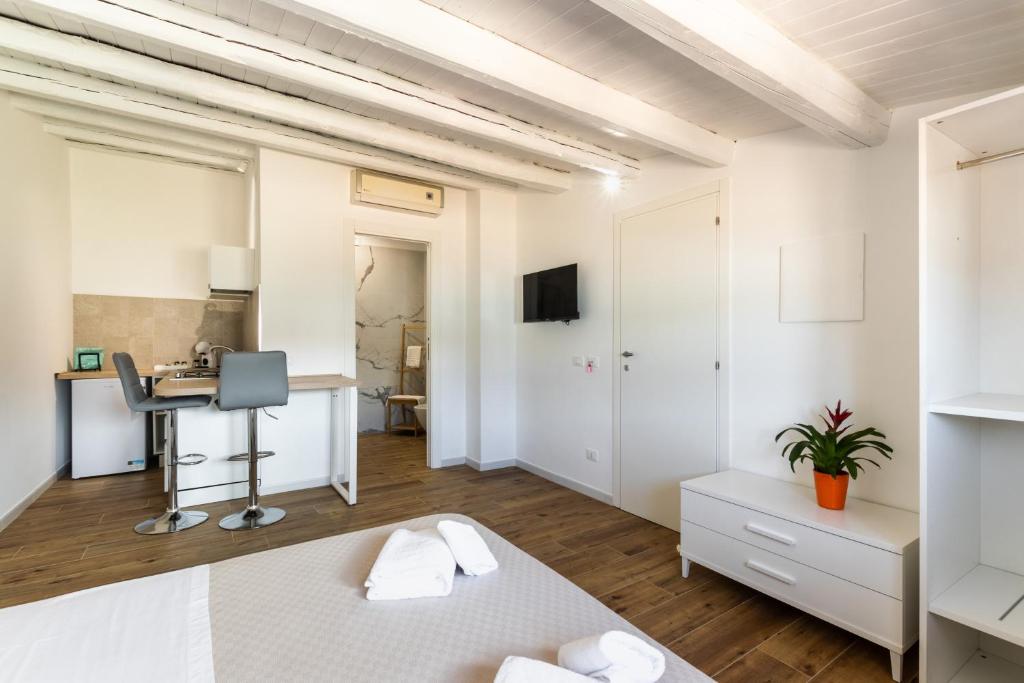 biała sypialnia z łóżkiem i biurkiem w obiekcie Trisina Rooms w mieście Avola