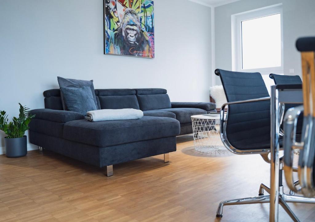 uma sala de estar com um sofá azul e cadeiras em Prime Park Family Deluxe Apartment Aschaffenburg em Aschaffenburg