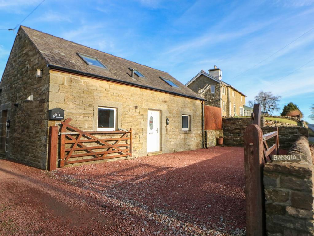 a stone barn with a wooden gate and a fence at Stable Cottage in Brampton