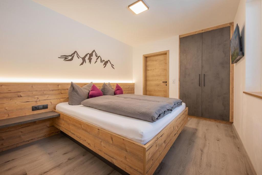 um quarto com uma cama de madeira e almofadas em Mountainlights Apartment em Neustift im Stubaital