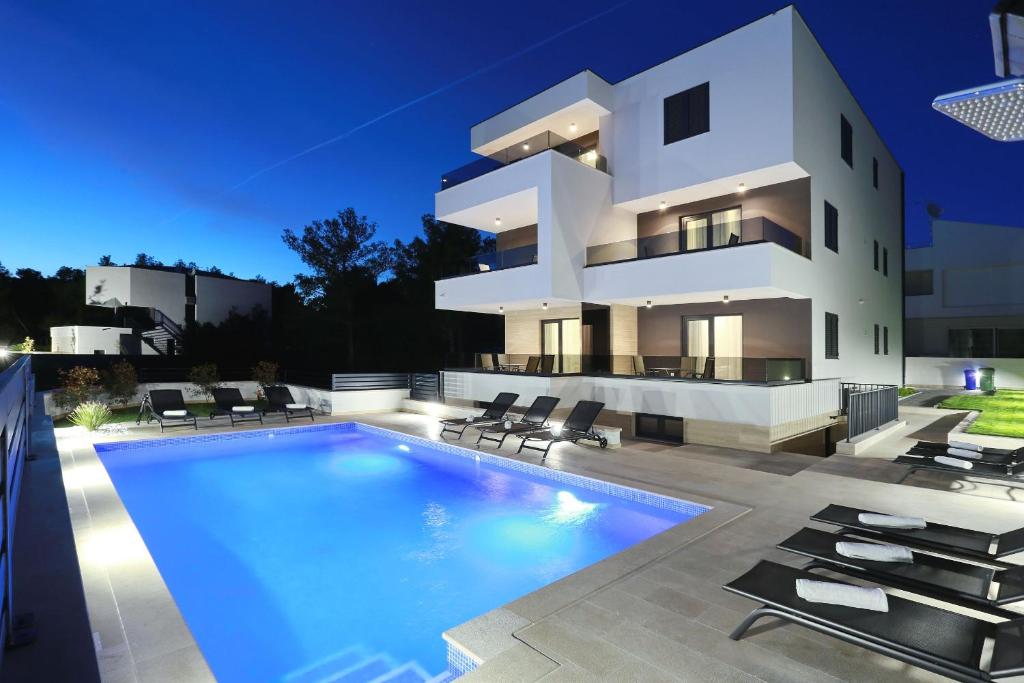 a large white house with a swimming pool in front of it at Villa Ankora 2 with heated pool in Biograd na Moru