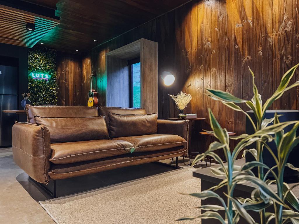 un sofá de cuero en una habitación con paredes de madera en LUTS Chalés, en Gonçalves