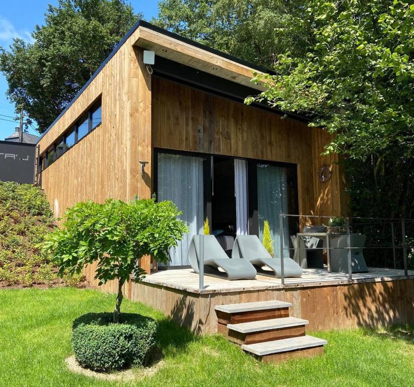 ein Holzhaus mit Stühlen und einem Baum im Hof in der Unterkunft Le Loft ATELIER in Fauvillers