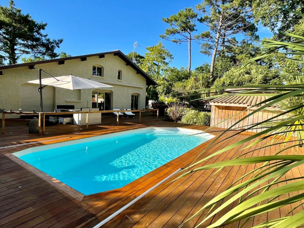 - une piscine sur une terrasse en bois avec une maison dans l'établissement Ferienhaus mit beheiztem Pool in Claouey, à Lège-Cap-Ferret