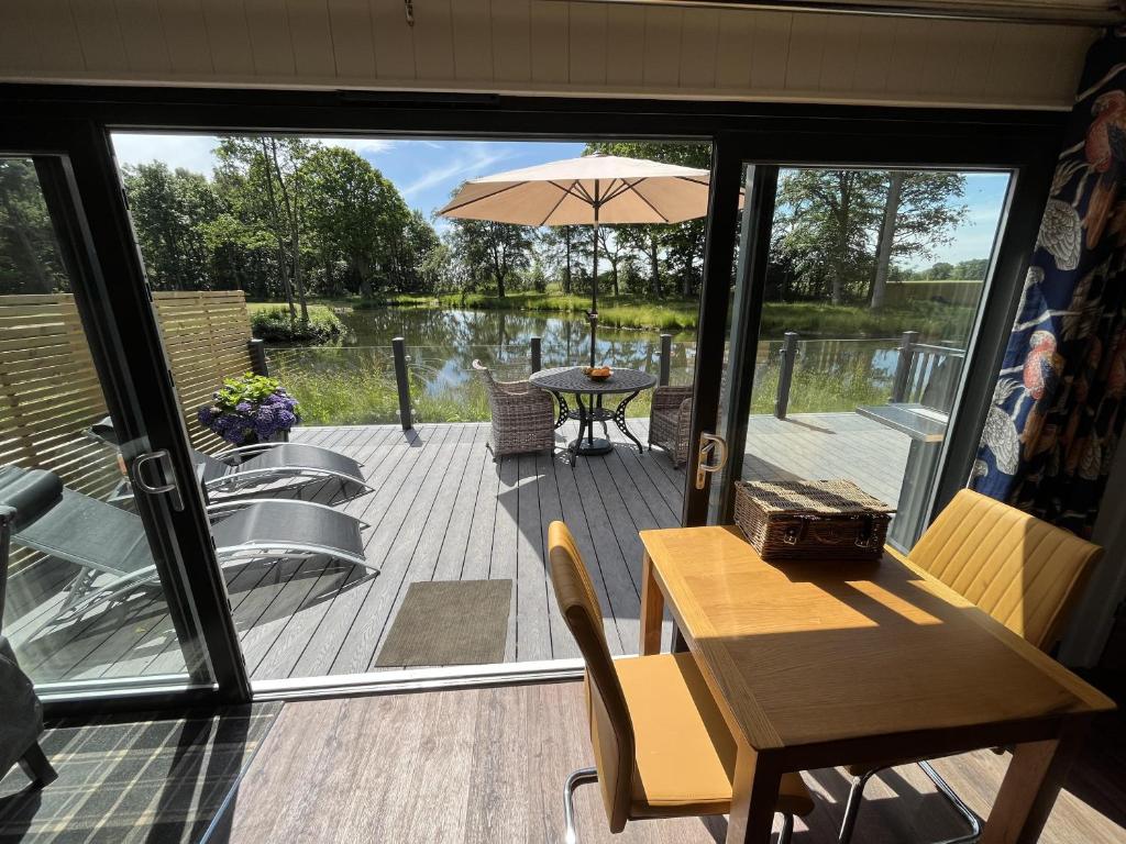 une terrasse avec une table et un parasol dans l'établissement Cedar Boutique Lodge-dog fishing and Spa access, à York