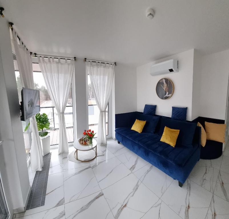 a living room with a blue couch and a tv at Apartament DoriSun-Lighthouse Mrzeżyno in Mrzeżyno