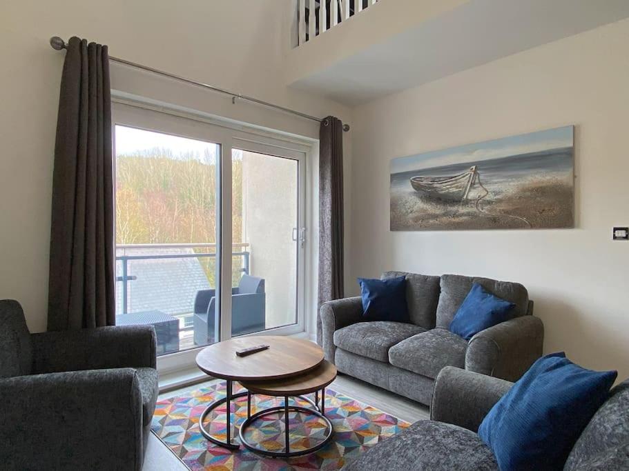 a living room with a couch and a table and a window at Modern Duplex Apartment with Woodland Views in Swansea