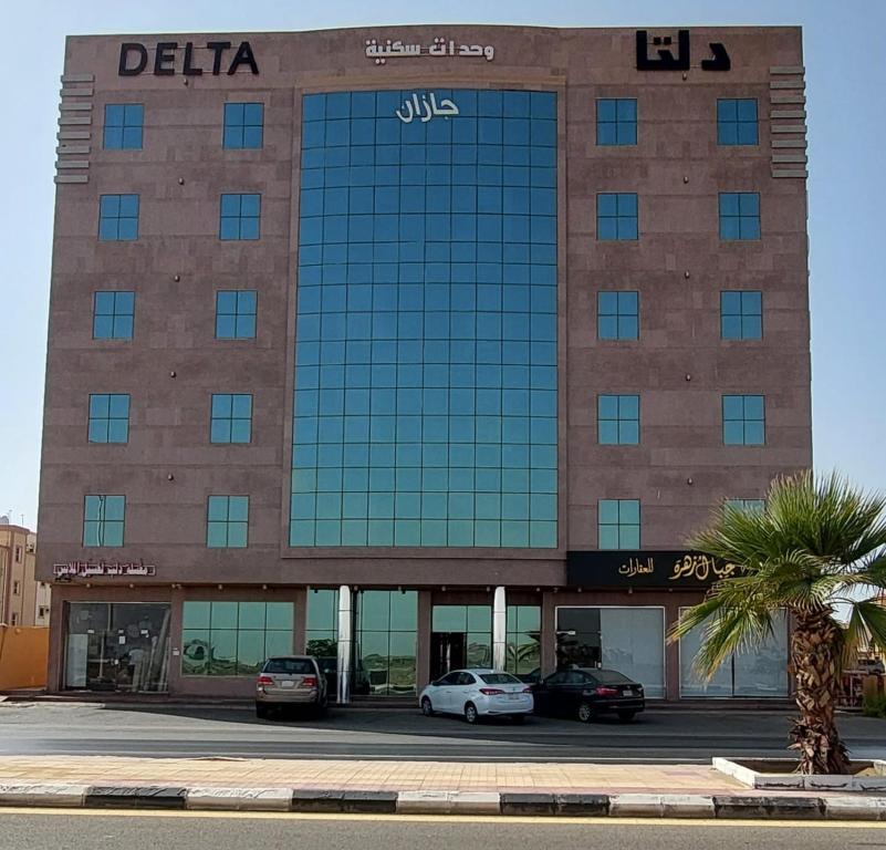 um grande edifício com carros estacionados em frente em Delta Hotel Suites em Jazan