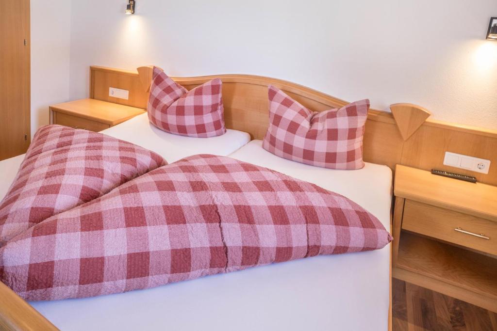 a bedroom with two beds with plaid pillows at Appartement Julia in Achenkirch