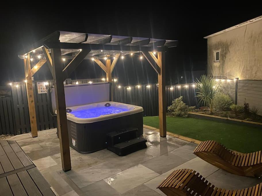 a hot tub under a gazebo in a yard at night at Casblaidd in Caernarfon