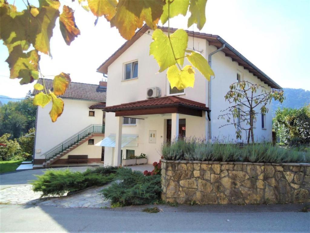 a large white house with a stone wall at Apartma Gorjan in Tolmin