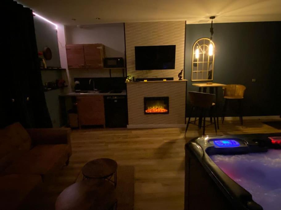 uma sala de estar com lareira e uma cozinha com mesa em Le privilège spa em Langeais