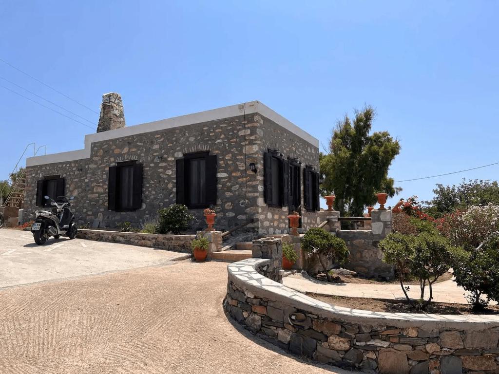una casa in pietra con una moto parcheggiata di fronte di Πέτρινο Εξοχικό Σπίτι στη Σύρο a Firókambos