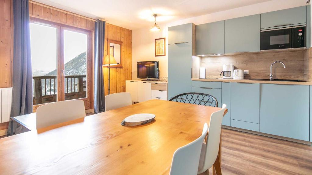 Il comprend une cuisine et une salle à manger avec une table et des chaises en bois. dans l'établissement Les Marmottes - 42 - Appart renove - 6 pers, à Saint-Sorlin-dʼArves