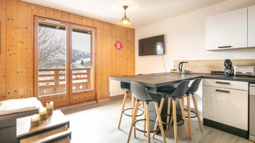 eine Küche mit einer Theke und Hockern in einem Zimmer in der Unterkunft Les Grizzlis - 28 - Appart modernise - 4 pers in Saint-Sorlin-dʼArves
