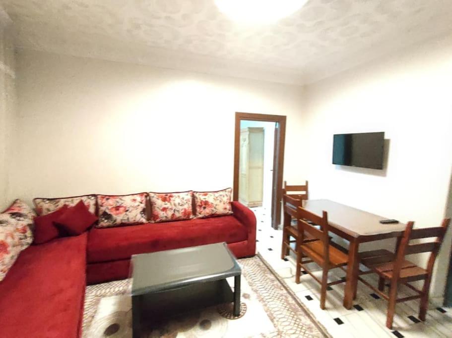 een woonkamer met een rode bank en een tafel bij City Centre Apartment - New Deco in Tanger