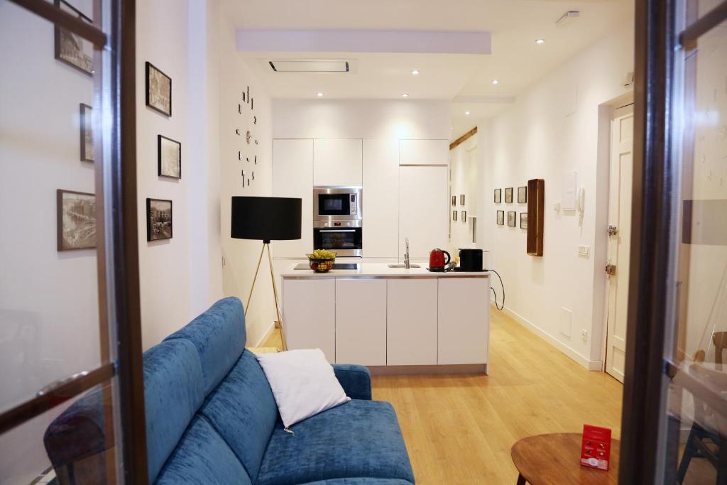 Il comprend un salon avec un canapé bleu et une cuisine. dans l'établissement Piso Moderno a 2 minutos del Casco Viejo con Parking Gratis, à Bilbao