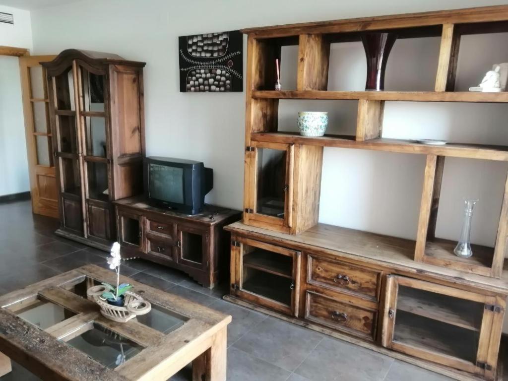 un soggiorno con scaffali in legno e TV di Apartamento Pepe a Alcantarilla