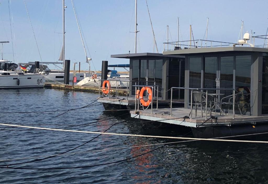 two boats are docked at a dock in the water at Hausboot Fjord Aquila mit Dachterrasse in Wendtorf in Wendtorf