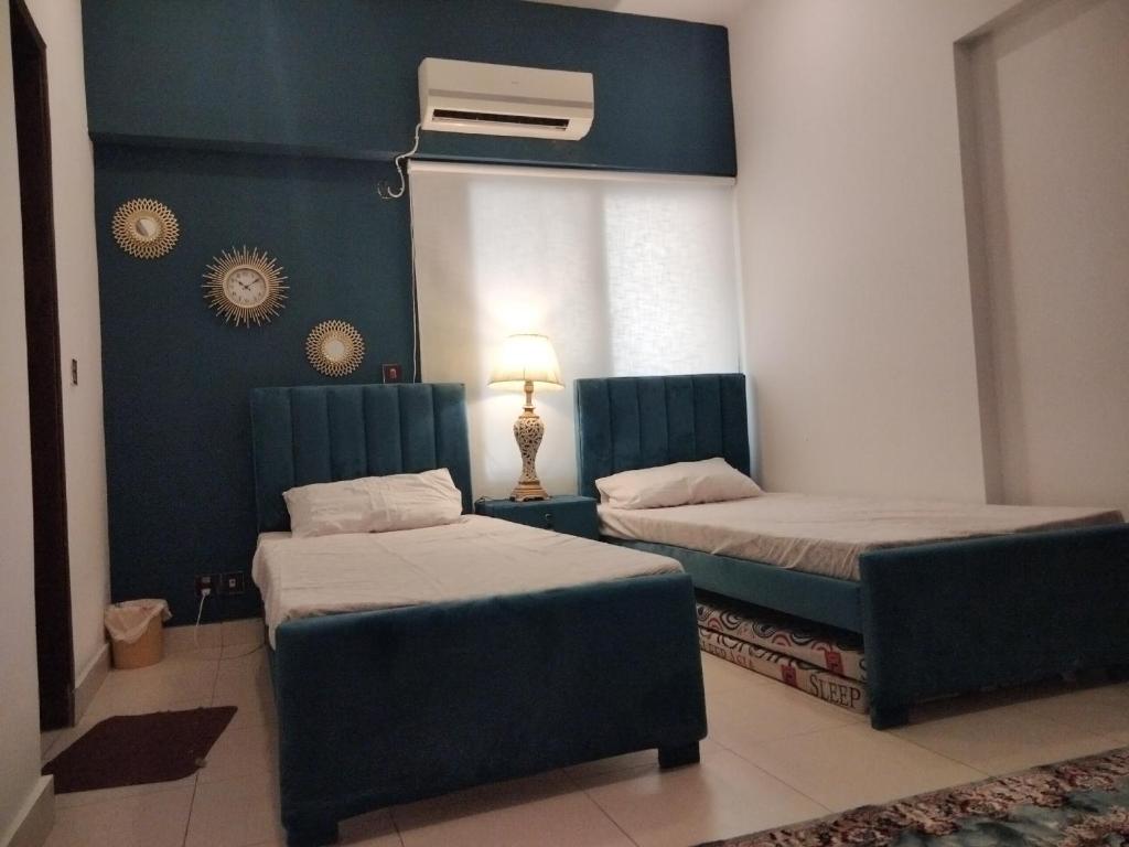 2 Betten in einem Zimmer mit blauen Wänden in der Unterkunft The Realtors Inn 2 BDR Apartment in Islamabad