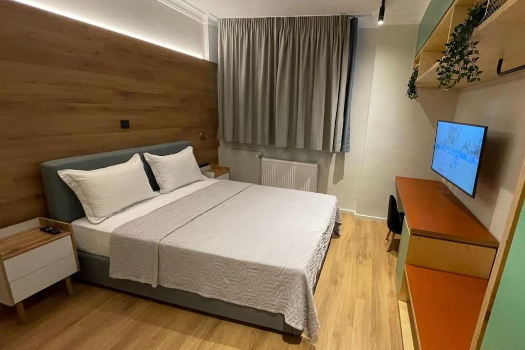 Dormitorio con cama, escritorio y TV en Athenian Aura Kolonaki - Feel Athens City Center, en Atenas