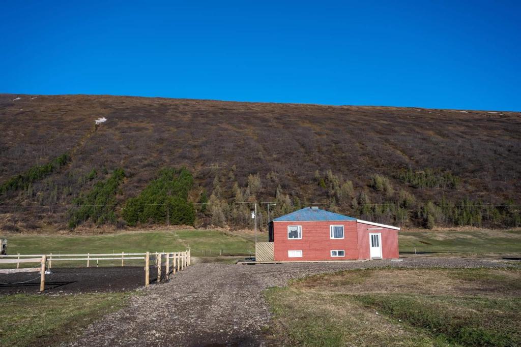 uma casa vermelha no lado de uma colina em Sandhaugar Guesthouse em Kiðagil