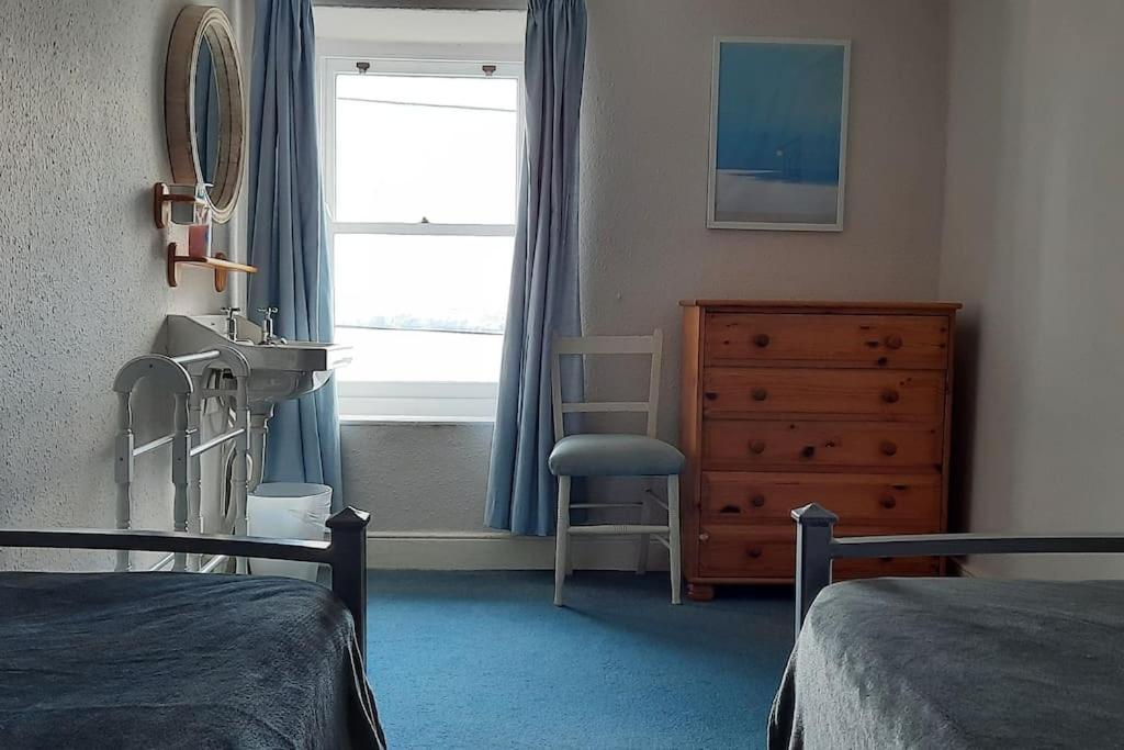a bedroom with two beds and a dresser and a window at Arvonia sleeps 7, sea views, dog friendly in New Quay