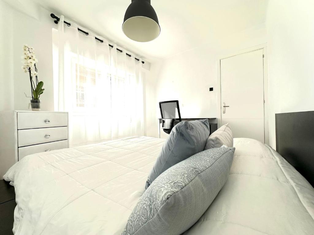 a white bedroom with a large white bed with pillows at Apartamento Cebra in Zaragoza