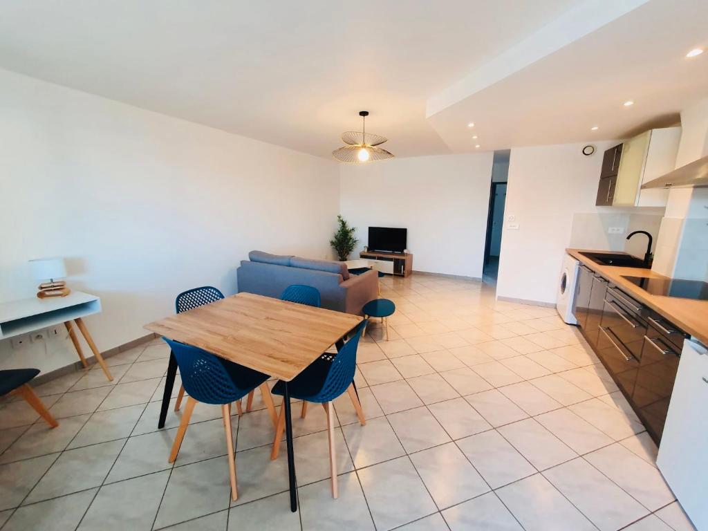 a kitchen and living room with a wooden table and chairs at Appartement moderne près de Toulouse in Fonsorbes