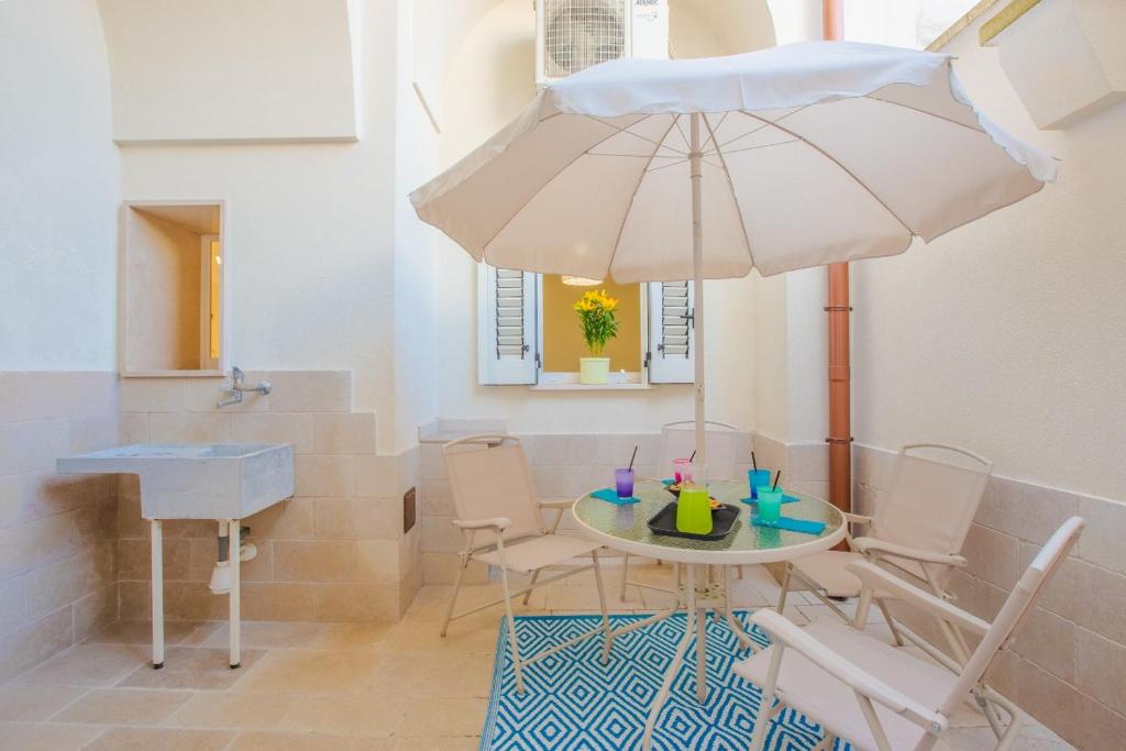 een eetkamer met een tafel en een paraplu bij Casa Ettore a 10' dalle spiagge in San Vito dei Normanni