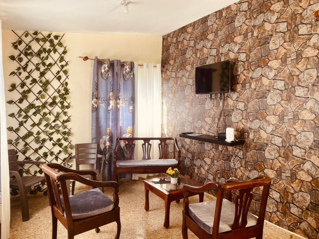 sala de estar con sillas y pared de piedra. en Lugar encantador en el Malecón Paraíso, Barahona., en Paraíso