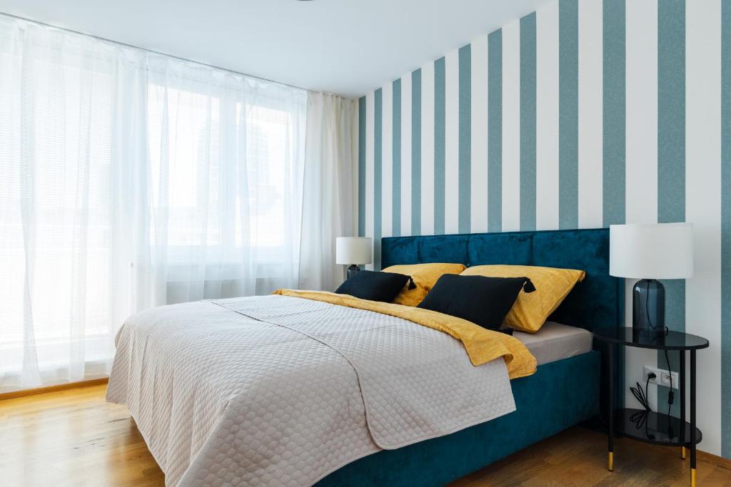 a bedroom with a blue bed with a striped wall at Business & Family Ambiente Apartments in Bratislava