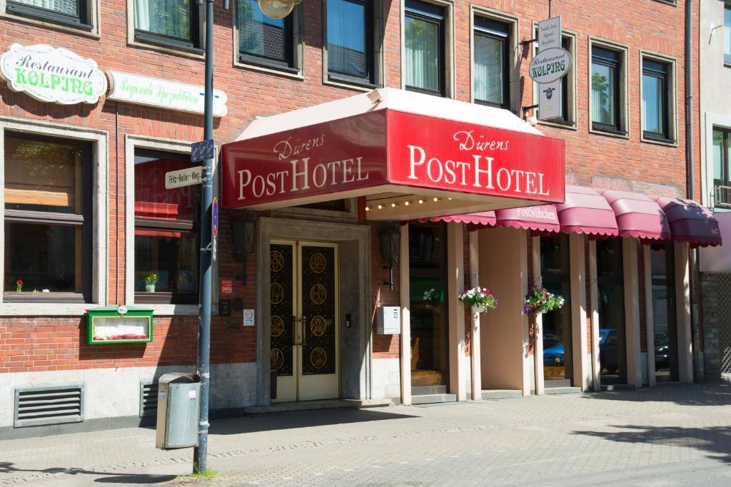 Trip Inn PostHotel Düren في دورين - إيفل: بيت بريد على شارع المدينة مع مظلات وردية