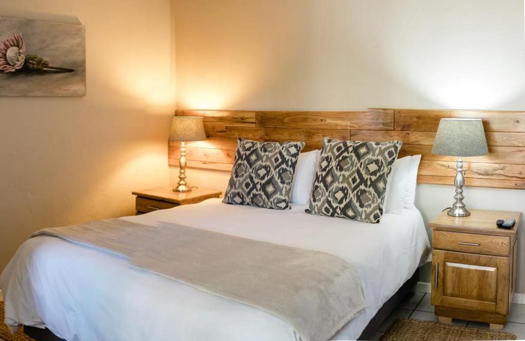 a bedroom with a large white bed with two lamps at St George's Guest House in Tzaneen