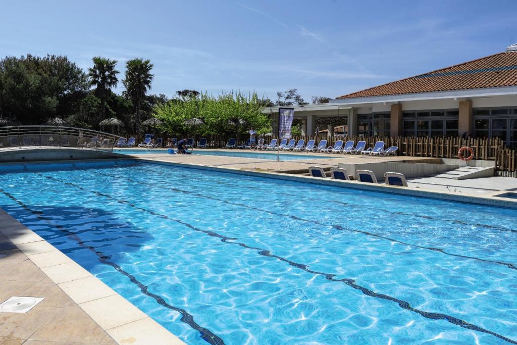 a large swimming pool with chairs and a hotel at Belambra Clubs Presqu&#39;île De Giens - Riviera Beach Club in Hyères