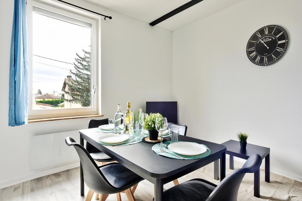 comedor con mesa negra, sillas y reloj en Appartement Le Cocon Bressan en Bourg-en-Bresse