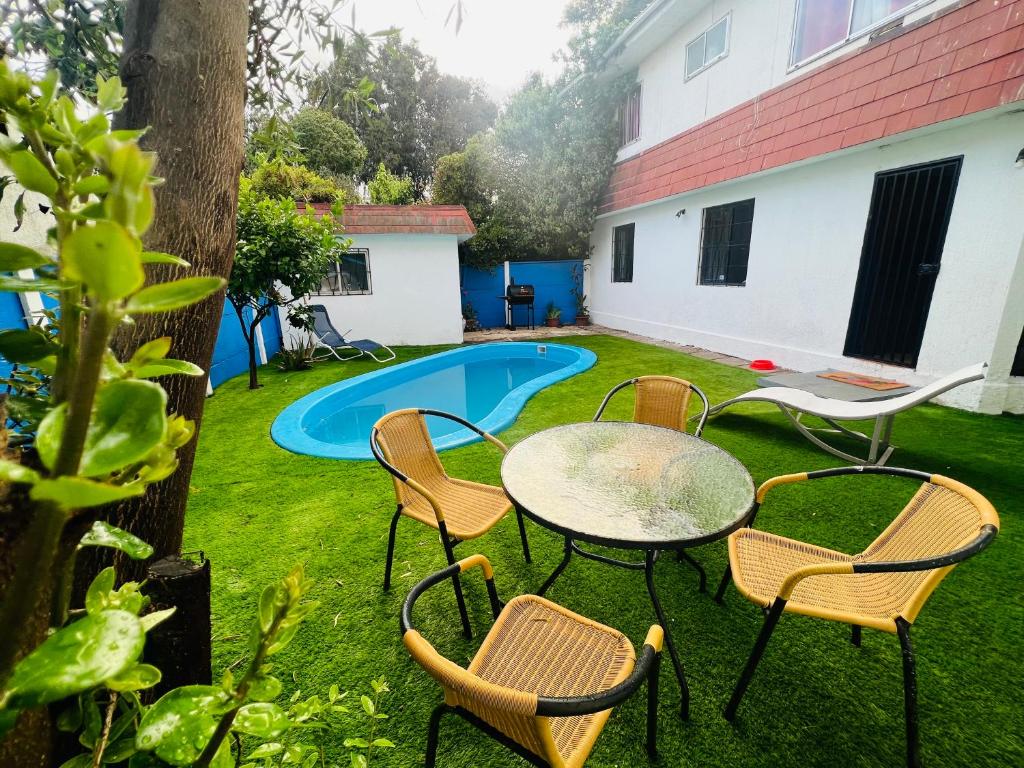 eine Terrasse mit einem Tisch, Stühlen und einem Pool in der Unterkunft Maravillosa Casa Con Piscina y Vista al Mar in Concón